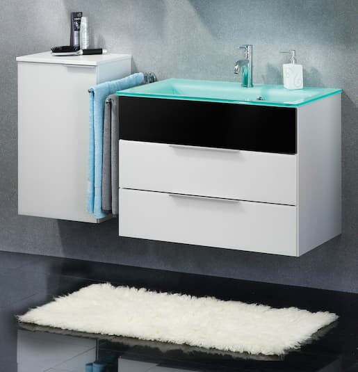 Grau-Schwarzes Bad mit einem weiß-schwarzem Waschtischunterschrank. Darauf befindet sich ein mintgrünes Glaswaschbecken.