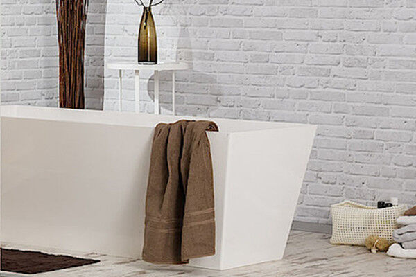 Ein braunes Handtuch hängt über einer weißen, eckigen Badewanne.